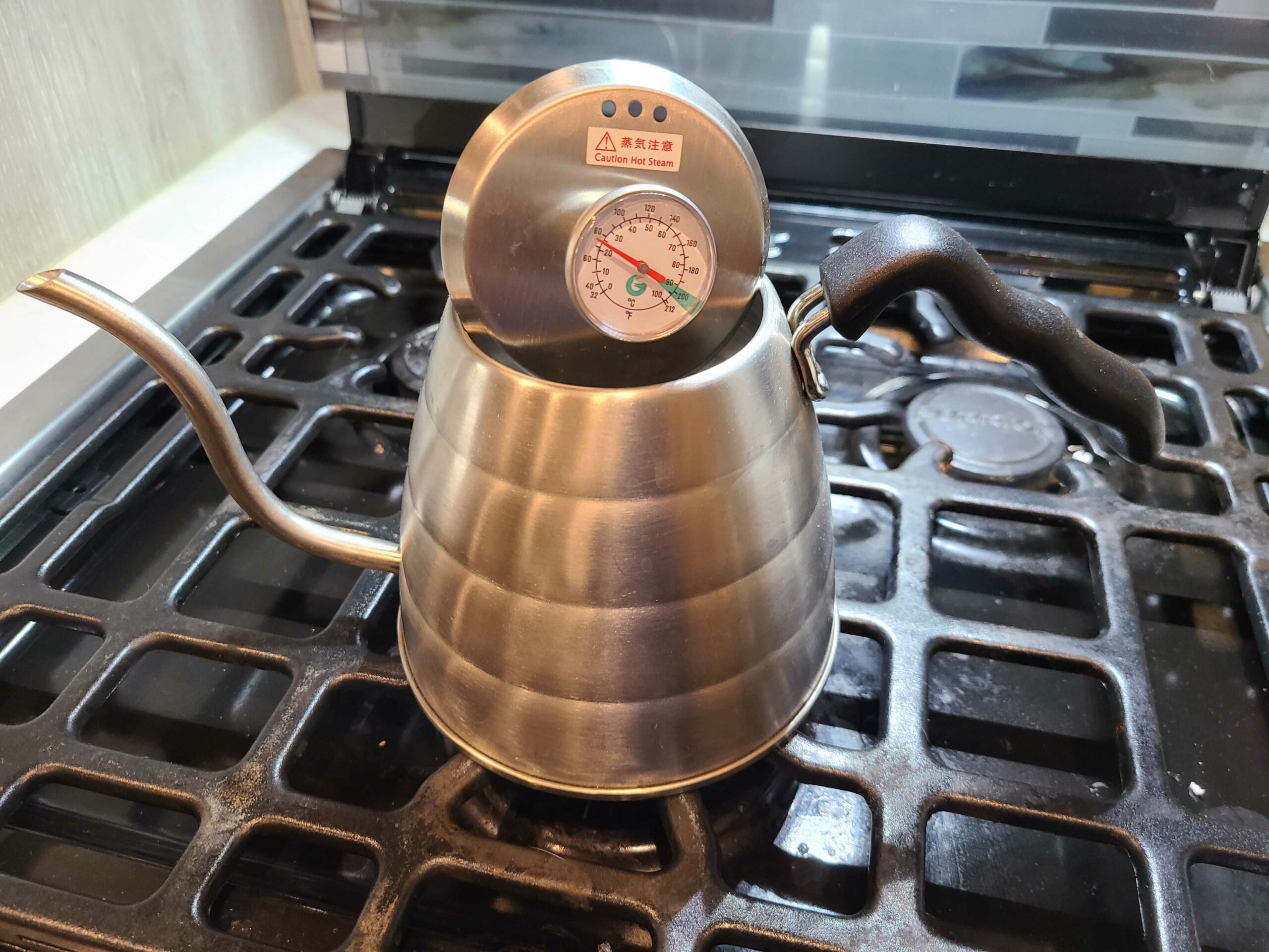 stainless steel gooseneck tea kettle on stove with thermometer lid