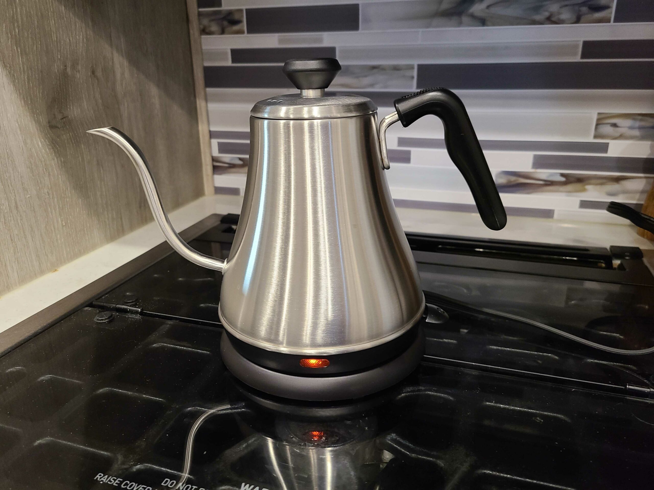 gooseneck stainless steel kettle on stove with indicator light on