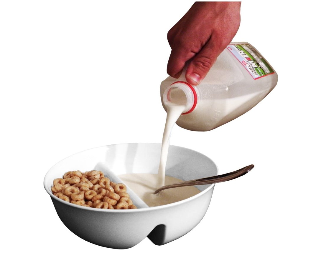 persons hand pouting milk into dual compartment milk and cereal bowl