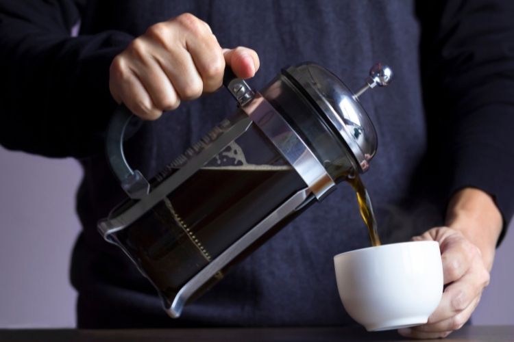 person pouring out of French Press Coffee Maker into mug