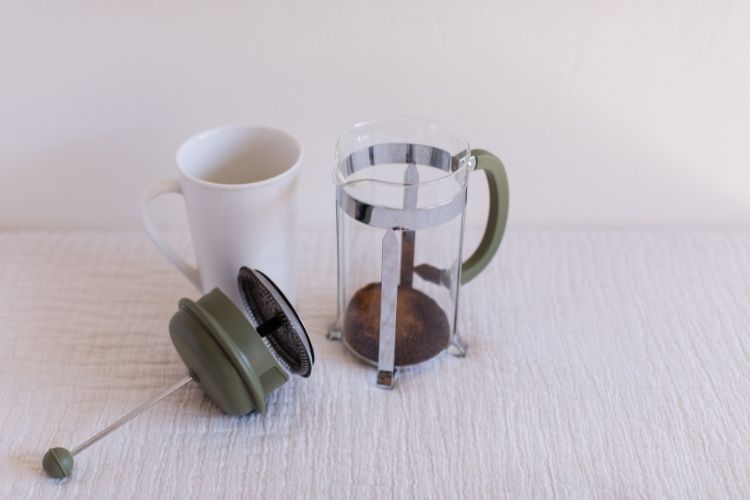 French Press Coffee Maker with lid off next to mug