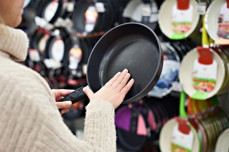 womans hand feeling frying pan in store