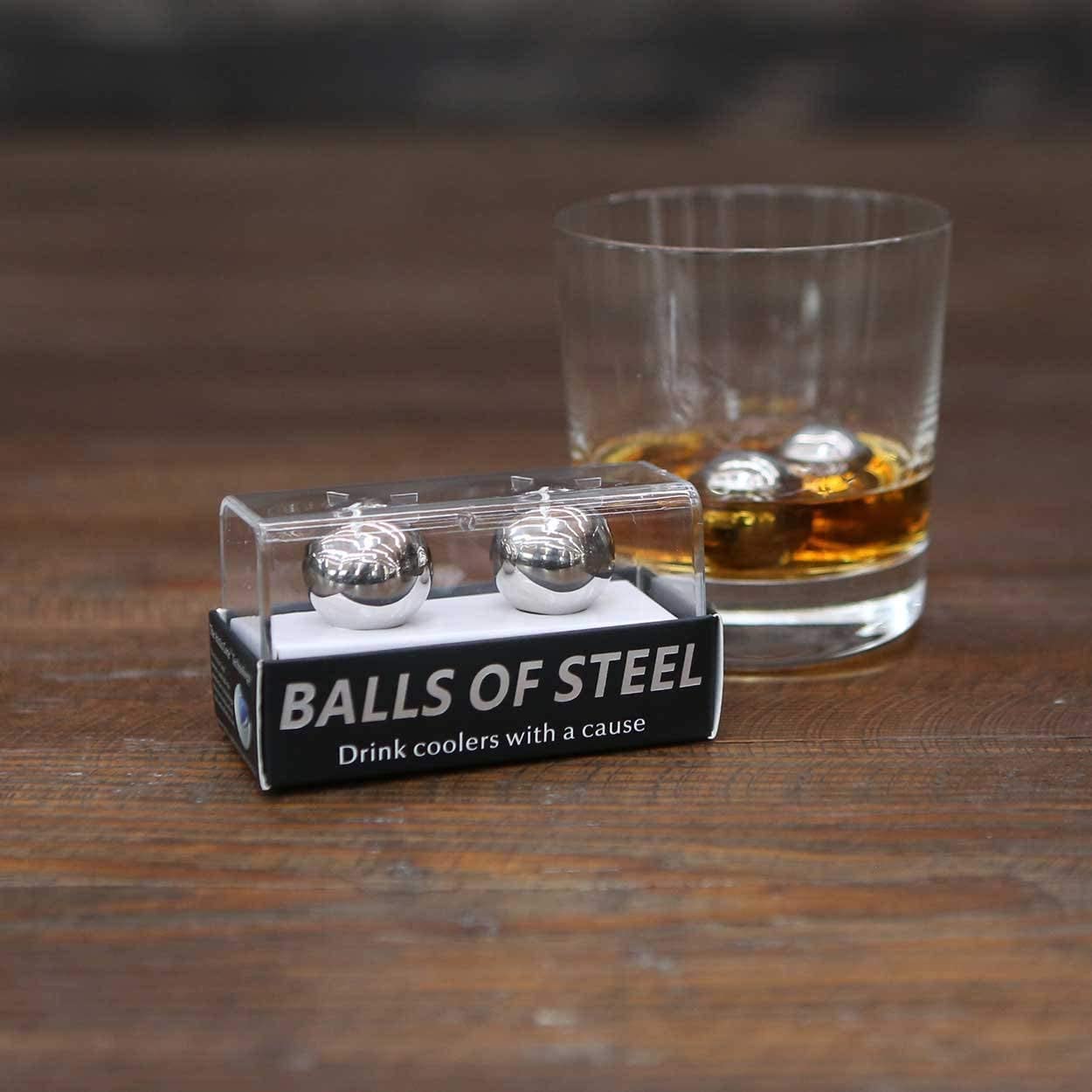 stainless steel whiskey balls in clear container next to glass of whiskey
