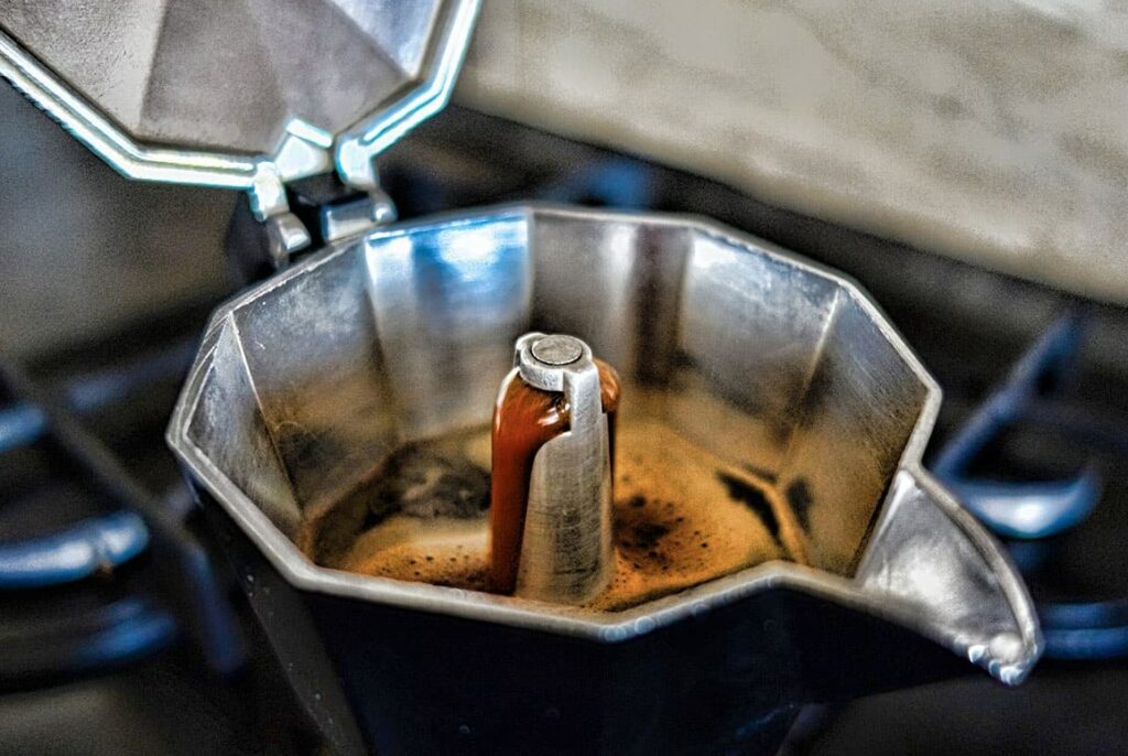 Open lid of espresso moka pot showing espresso brewing