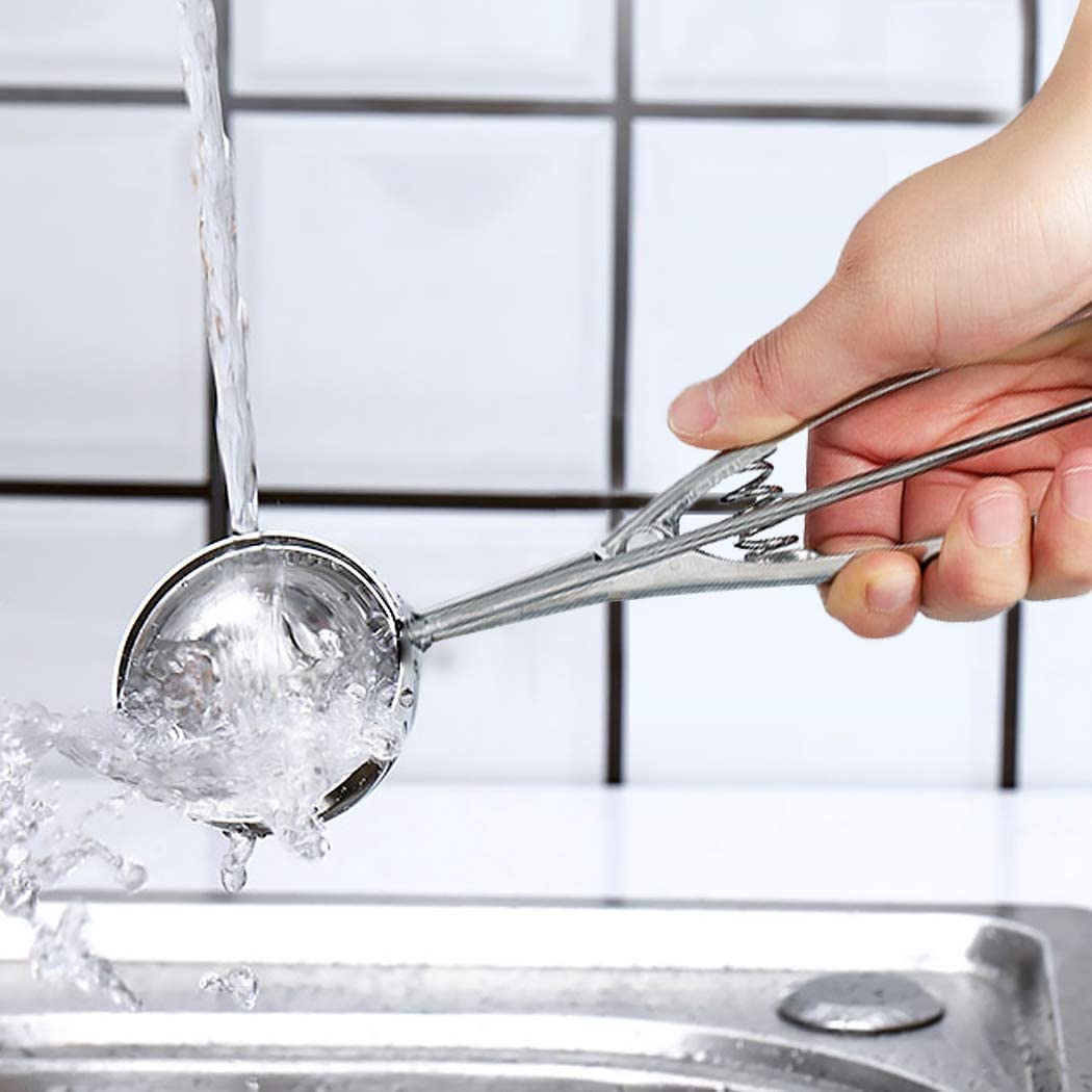 person holding stainless steel trigger ice cream scoop under running water