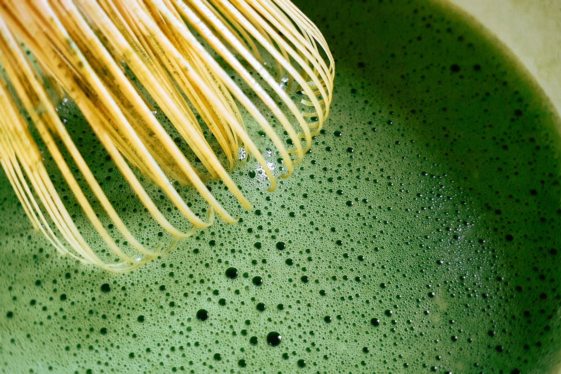 close up of bamboo whisk in matcha