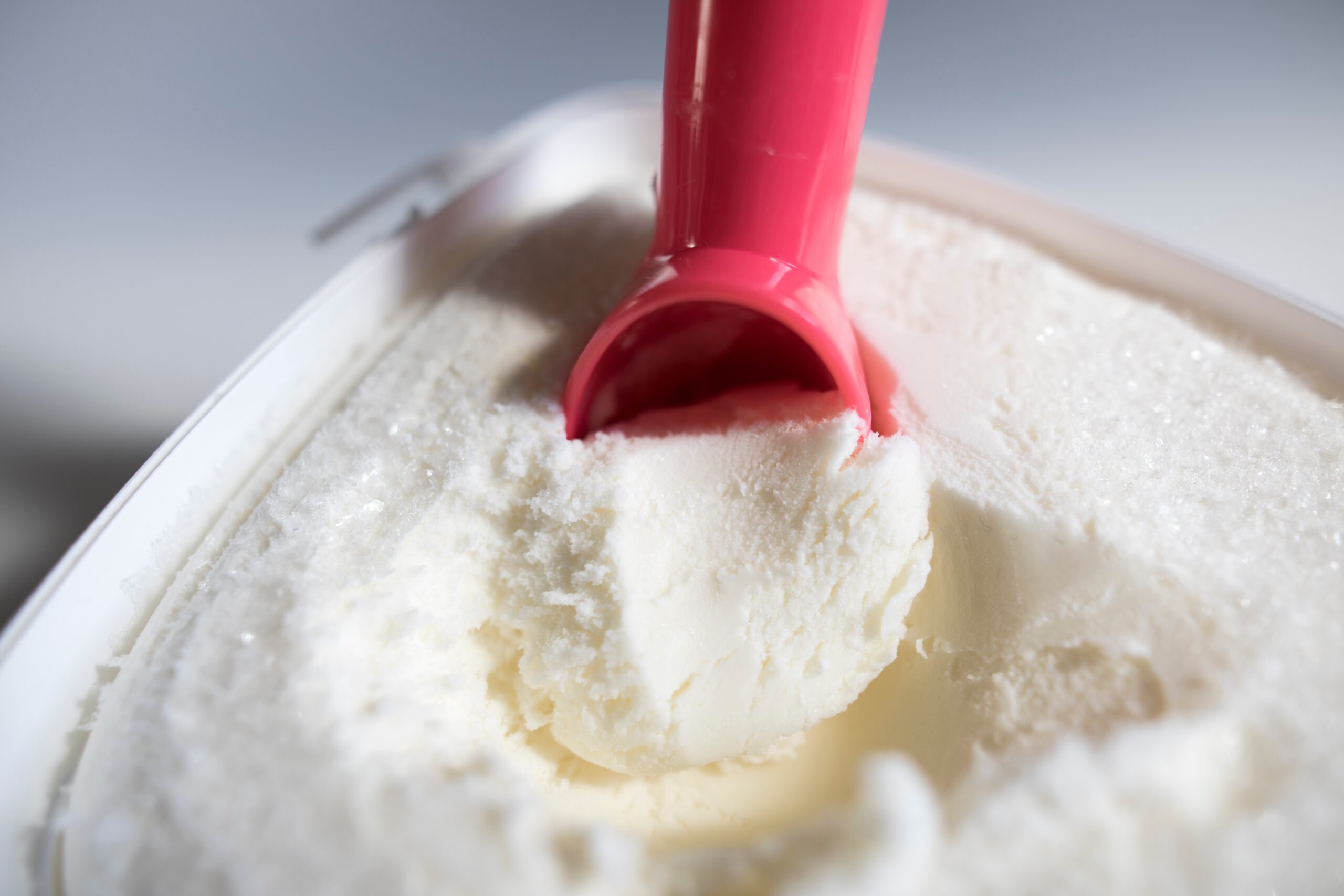 close up of red ice cream scoop scooping vanilla ice cream