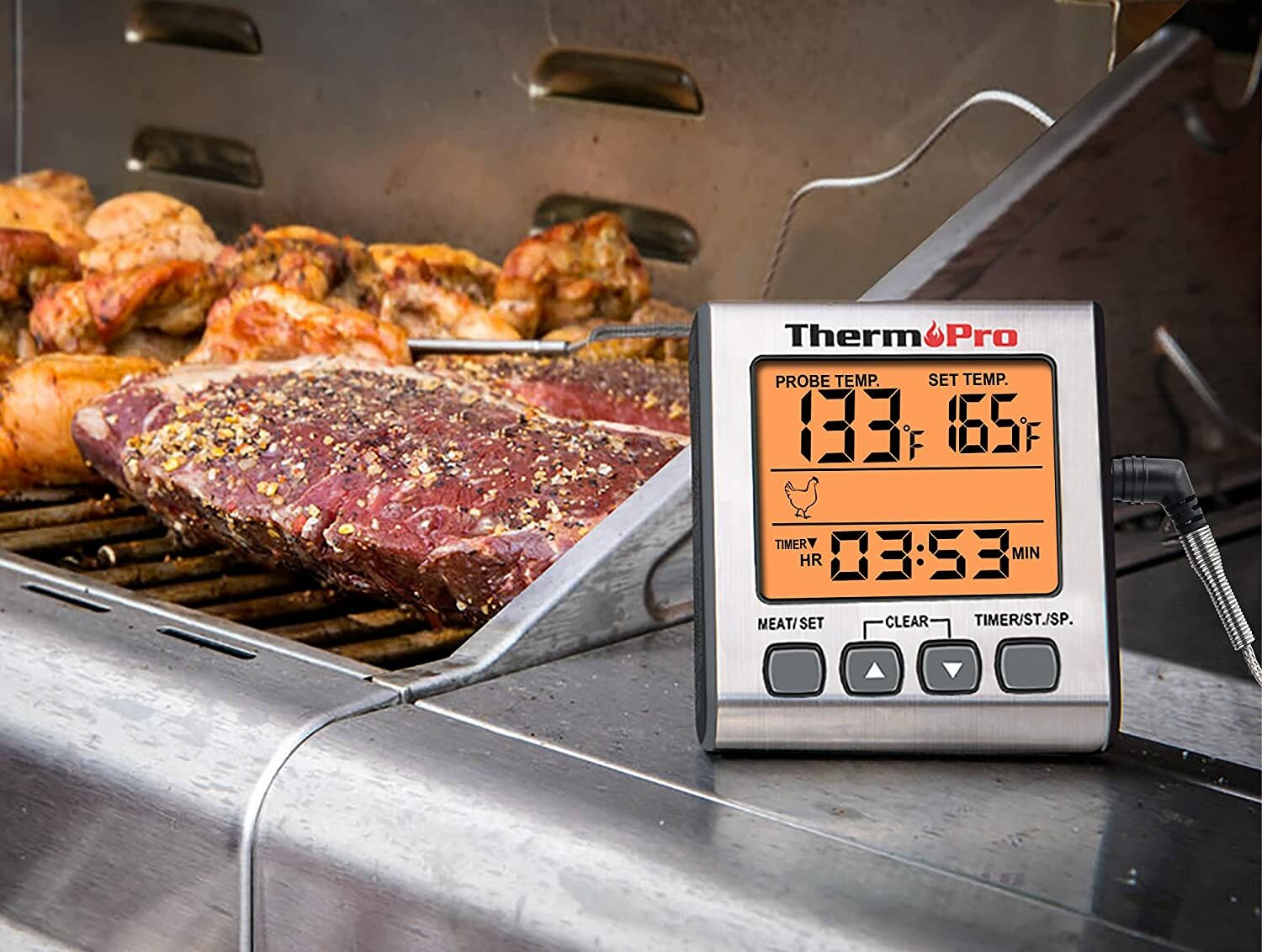 meat and chicken on grill with digital thermometer in focus