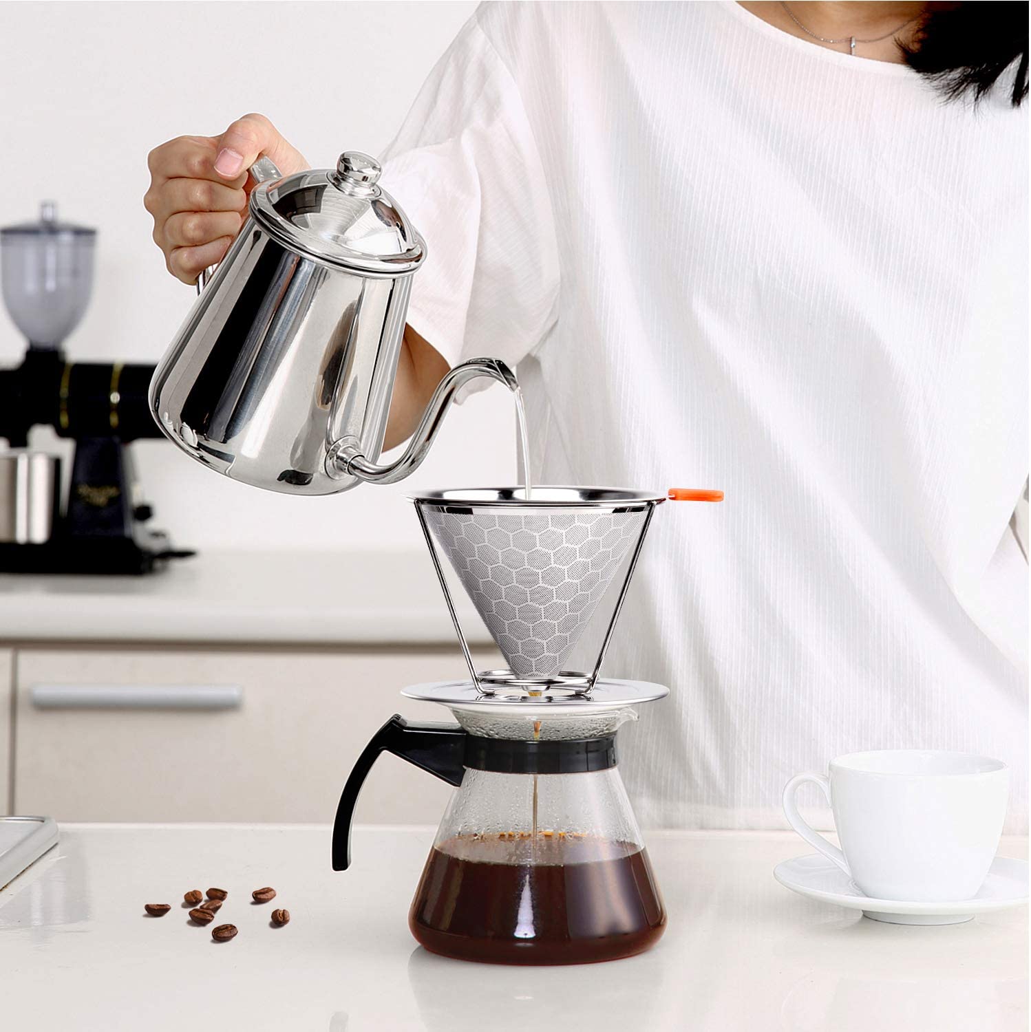 woman pouring water into pour over coffee maker with stainless steel coffee filter
