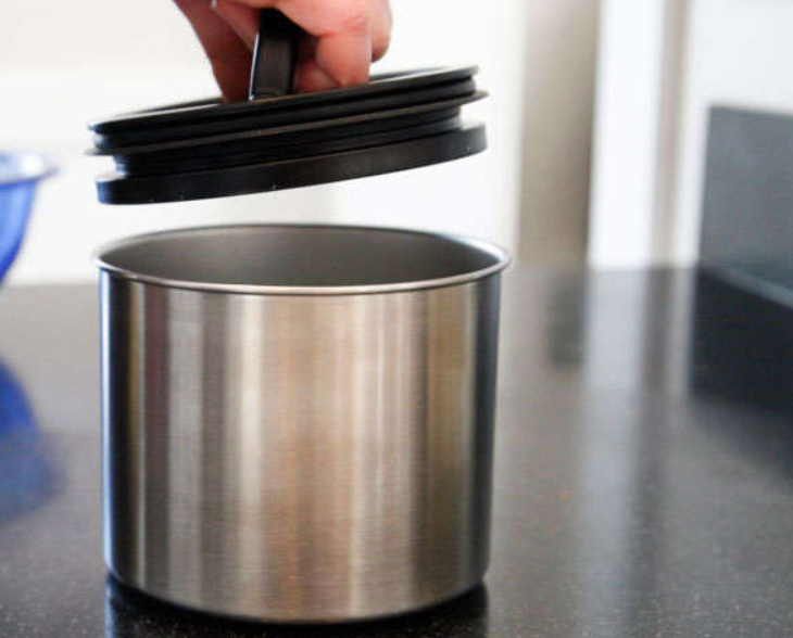 persons hand putting lid on stainless steel coffee canister