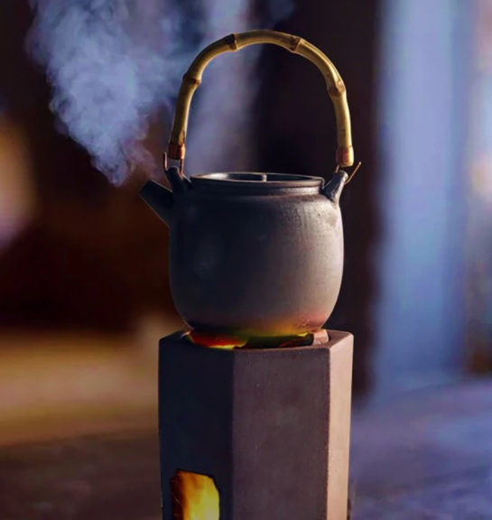 steaming ceramic tea kettle over fire