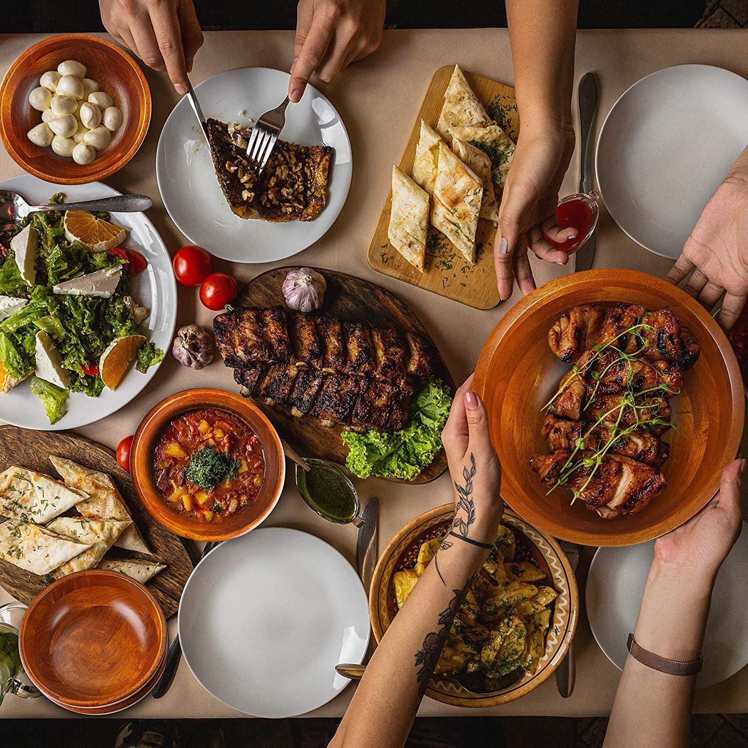 flatlay of table full of food with peoples hands reaching in