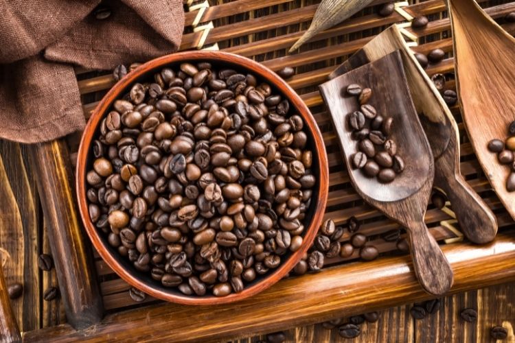 coffee beans in bowl with wooden spoon