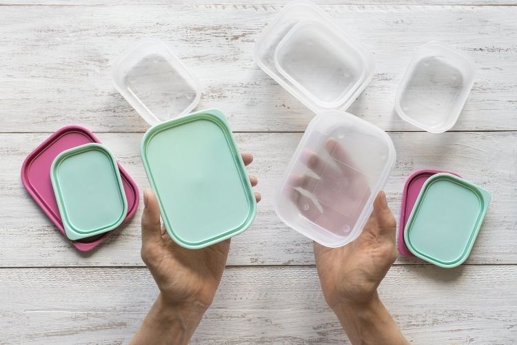 hands holding open food storage containers with lids