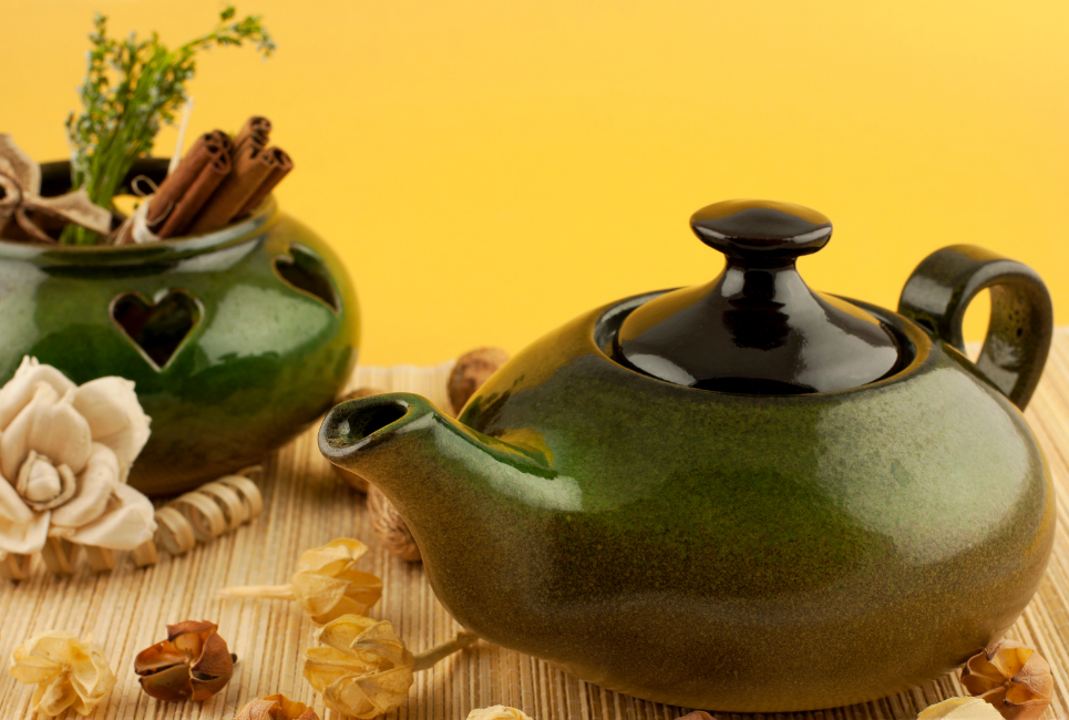 green ceramic tea kettle styled on natural tablescape in front of yellow wall