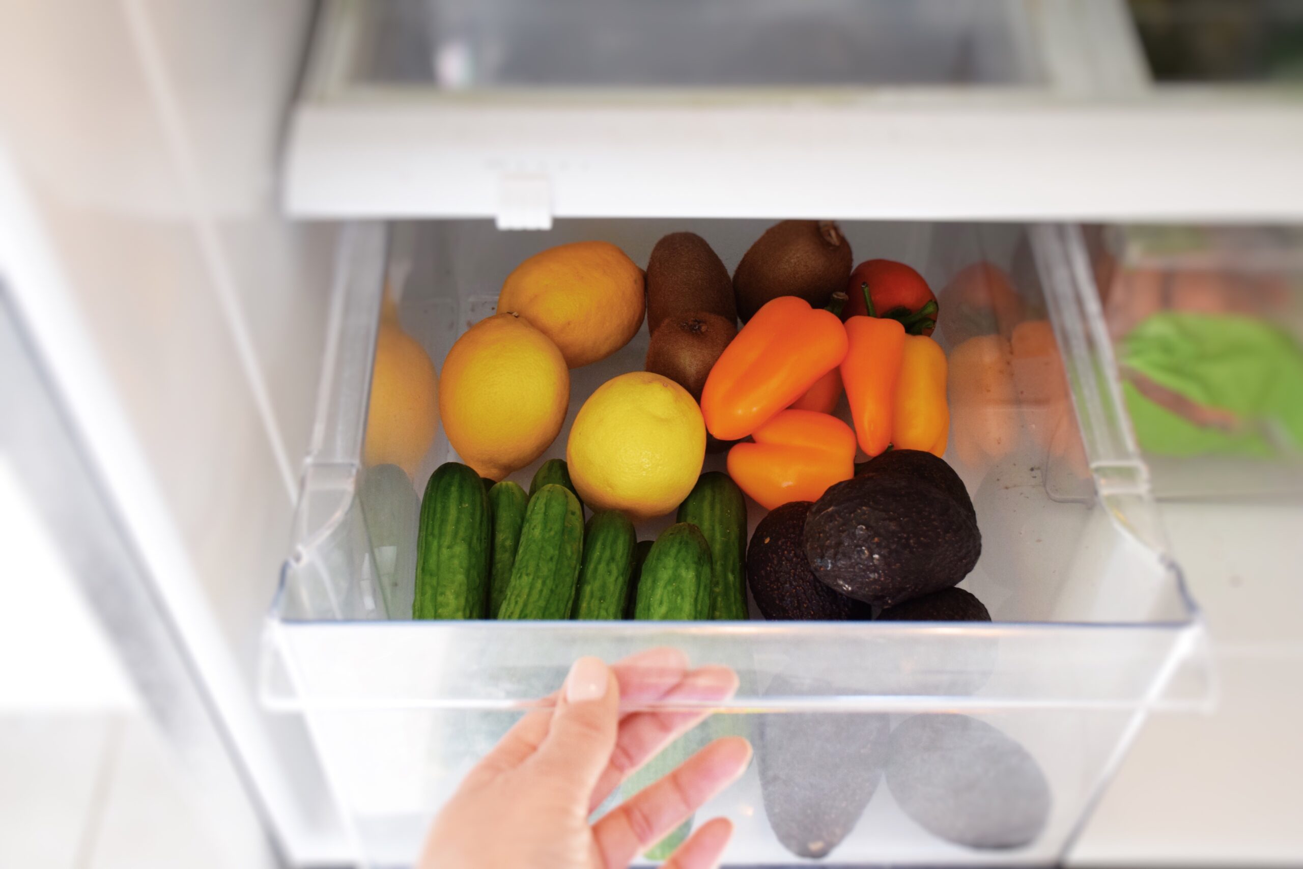 persons hand opening fruit drawer in freezer